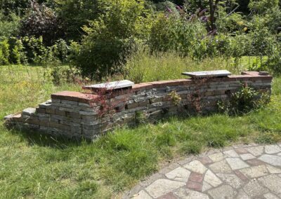 Keermuur van gestapelde natuursteen met afdeklaag van hergebruikte bakstenen