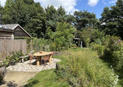 Overzicht van de natuurlijke tuin met terras van gebroken natuursteen en bloemenweide
