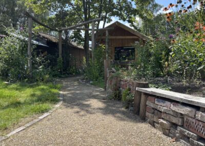 Zicht door de houten pergola op het tuinhuis met terras