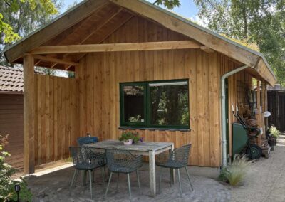 Houten tuinschuur met overkapping en terras met eettafel